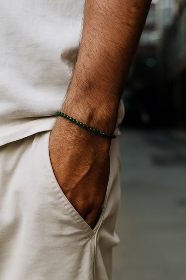 A close-up of a male model's wrist showcasing the 4mm jade bracelet paired with neutral-toned linen trousers.
