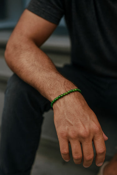 A lifestyle shot of a male model wearing a 4mm jade bead bracelet, highlighting its subtle profile and vibrant green color in a casual setting.
