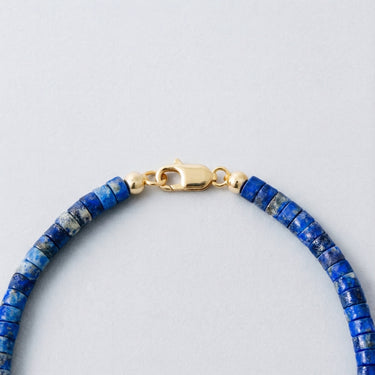 Close-up of a men’s 4mm lapis heshi necklace featuring a polished 14K gold-filled lobster clasp.
