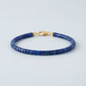 A 4mm Lapis Lazuli heishi bead bracelet with a high-polish gold lobster clasp, displayed against a light grey background.
