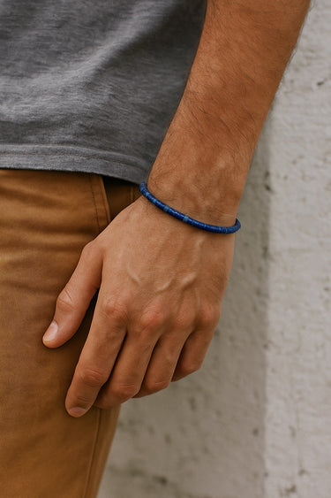 A male model's wrist showcasing the deep blue tones and low-profile fit of a 4mm Lapis Lazuli heishi bead bracelet.
