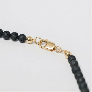Close-up of a men’s necklace with 4mm porous lava beads and a polished 14K gold-filled lobster clasp.