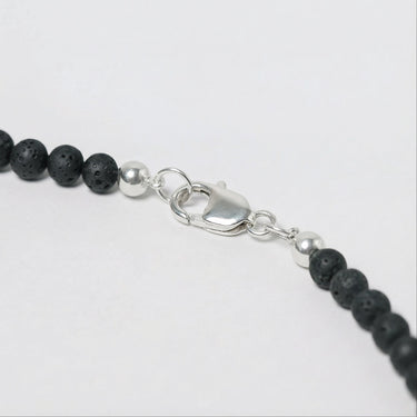 Close-up of a men’s necklace with 4mm porous lava beads and a polished sterling silver lobster clasp.