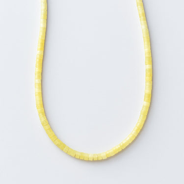 A single strand of 4mm pale yellow lemon jade heishi beads displayed in a U-shape against a neutral light grey background.
