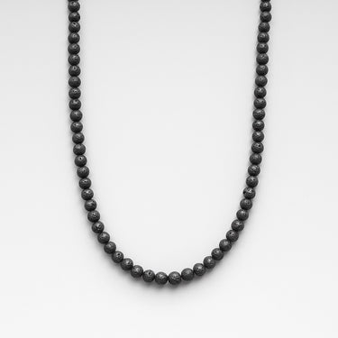 A strand of 4mm porous black lava beads displayed in a U-shape against a neutral light grey background.
