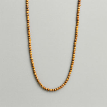 A strand of 4mm earth-toned picture jasper beads displayed in a U-shape against a neutral light grey background.
