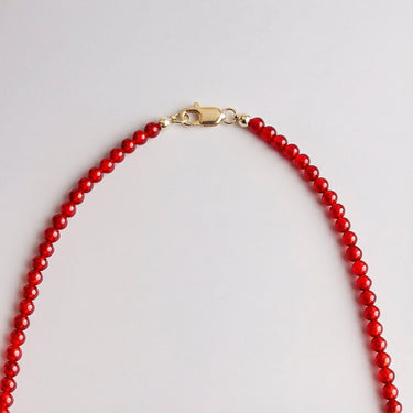 Close-up of a men’s necklace with 4mm red agate beads and a polished 14K gold-filled lobster clasp.