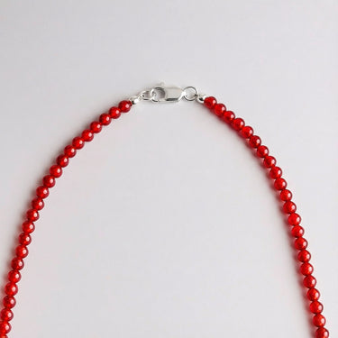 Close-up of a men’s necklace with 4mm red agate beads and a polished sterling silver lobster clasp.