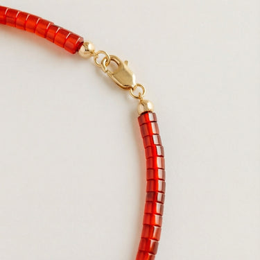 Close-up of a men’s 4mm red agate heshi necklace featuring a polished 14K gold-filled lobster clasp.

