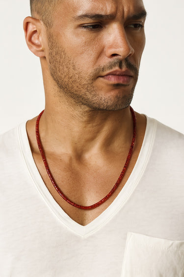 Front view of a model wearing a minimalist 4mm red agate heshi necklace styled with a white v-neck t-shirt.
