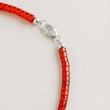 Close-up of a men’s 4mm red agate heshi necklace featuring a polished sterling silver lobster clasp.

