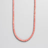 A single strand of 4mm dusty pink Rhodonite heishi beads displayed in a U-shape against a neutral light grey background.
