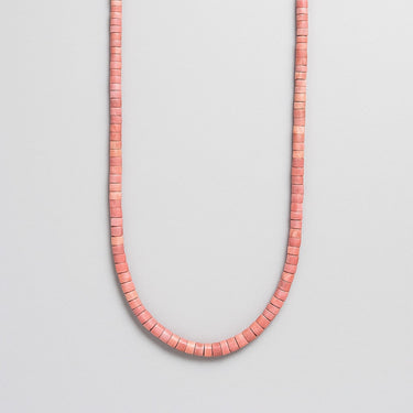 A single strand of 4mm dusty pink Rhodonite heishi beads displayed in a U-shape against a neutral light grey background.
