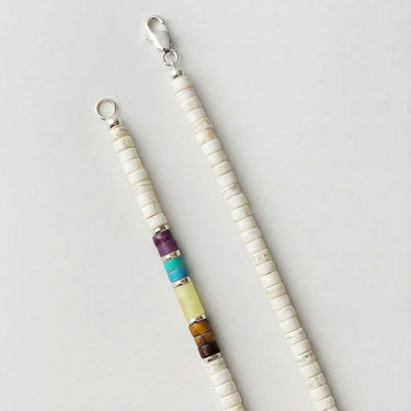 Detailed view of a men's 4mm white turquoise heshi necklace featuring an accent section of amethyst, blue turquoise, lemon jade, and tiger's eye beads separated by sterling silver spacers.
