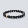 A 6mm Black Lava round bead bracelet featuring a porous volcanic texture and a single 14K gold-filled accent bead.

