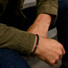 A lifestyle shot of a male model wearing a 6mm Gloss Black Onyx bracelet, showcasing its deep obsidian color and high-shine finish.
