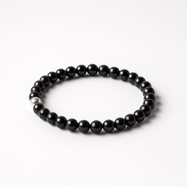 A top-down view of a 6mm Gloss Black Onyx bead bracelet, emphasizing its consistent deep black tone and mirror-like polish.
