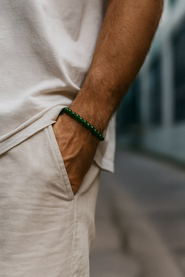 A lifestyle shot of a male model wearing a 6mm jade bracelet, demonstrating its versatile, slim profile with neutral summer attire.
