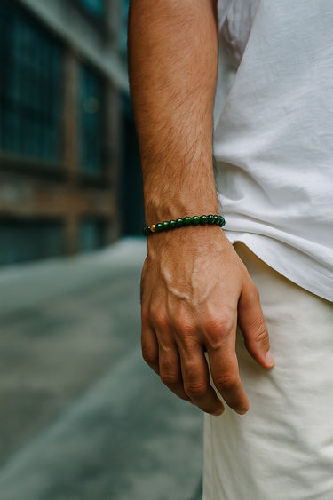 A close-up of a male model's wrist showcasing the vibrant green tones and 6mm scale of a jade bead bracelet.
