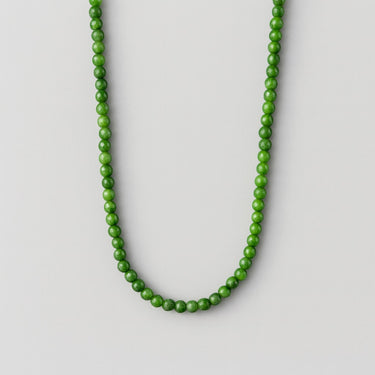 A single strand of 6mm deep green Nephrite Jade beads displayed in a U-shape against a neutral light grey background.

