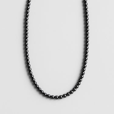 A strand of 6mm high-gloss black onyx beads displayed in a U-shape against a neutral background.
