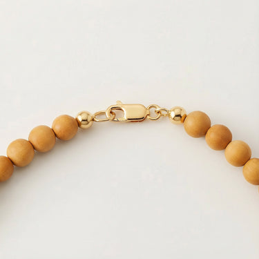 Close-up of a men’s necklace with 6mm round golden sandalwood beads and a polished 14K gold-filled lobster clasp.