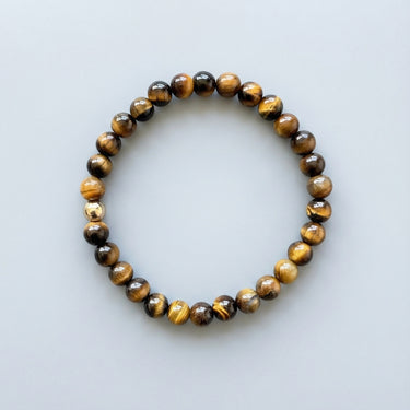 A 6mm Tiger's Eye round bead bracelet featuring shimmering golden-brown tones and a single 14K gold-filled accent bead.
