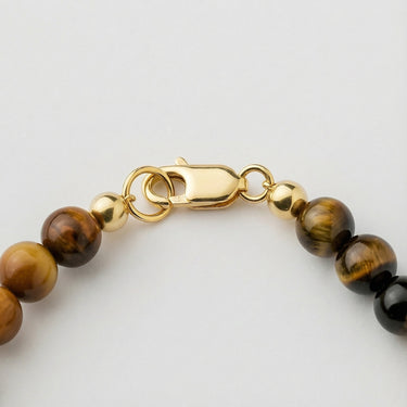 Close-up of a men’s necklace with 6mm tiger's eye beads and a polished 14K gold-filled lobster clasp.
