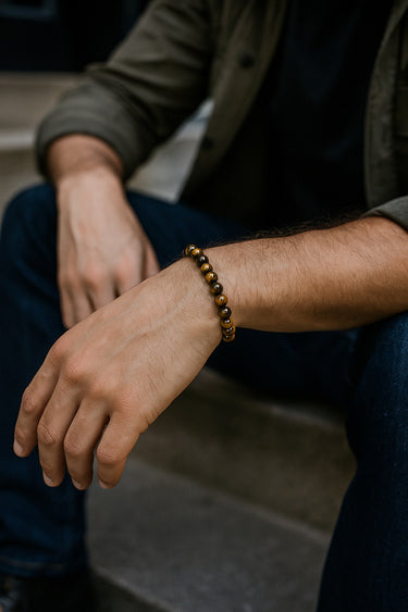 A lifestyle shot of a male model wearing a 6mm Tiger's Eye bead bracelet, highlighting its natural chatoyancy and slim, versatile profile.
