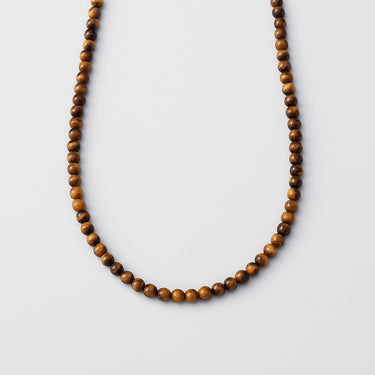 A single strand of 6mm golden-brown Tiger's Eye beads displayed in a U-shape against a neutral light grey background.
