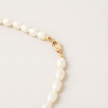 Close-up of a men’s necklace with 7-8mm white freshwater pearls and a polished 14K gold-filled lobster clasp.