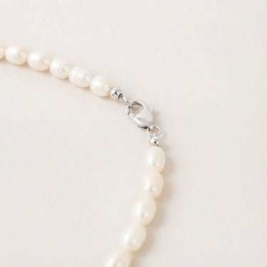 Close-up of a men’s necklace with 7-8mm white freshwater pearls and a polished sterling silver lobster clasp.