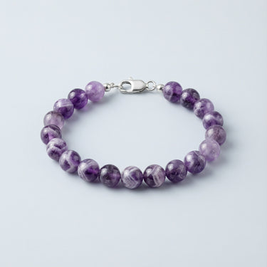 An 8mm Amethyst round bead bracelet featuring vibrant purple tones and a high-polish silver lobster clasp, displayed against a light grey background.
