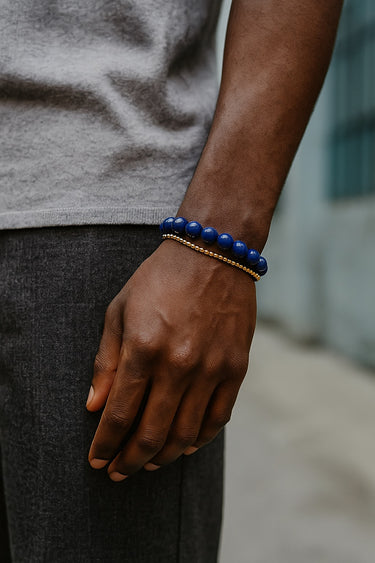 A close-up of a male model's wrist showcasing the deep blue tones and natural gold pyrite flecks of an 8mm Lapis Lazuli bead bracelet.
