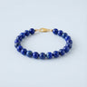 An 8mm Lapis Lazuli round bead bracelet featuring deep blue stones with golden pyrite flecks and a high-polish gold lobster clasp.
