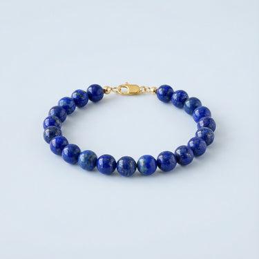 An 8mm Lapis Lazuli round bead bracelet featuring deep blue stones with golden pyrite flecks and a high-polish gold lobster clasp.
