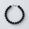 An 8mm matte black onyx round bead bracelet featuring a high-polish silver lobster clasp, displayed against a light grey background.
