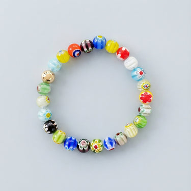 An 8mm handmade Millefiori glass bead bracelet featuring a kaleidoscope of floral patterns and a single 14k gold accent bead.
