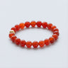 An 8mm Red Agate round bead bracelet featuring vibrant crimson stones and a single 14k gold filled accent bead, displayed against a light grey background.
