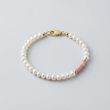 A mixed-media bracelet featuring white baroque pearls, pink petrified rhodonite heishi beads, and 14K gold-filled accents with a gold lobster clasp.
