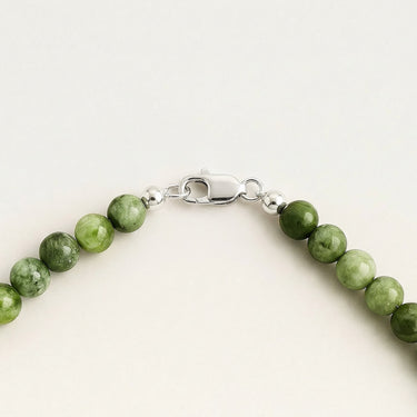 Close-up of chrome diopside gemstone beads with sterling silver accent beads and lobster clasp detail on a white background.