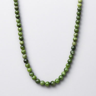 A necklace made with 6mm forest-green Chrome Diopside beads displayed in a U-shape against a white background.
