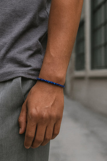 A close-up of a male model's wrist showcasing the sharp geometric silhouette and rich blue hues of a 3mm Lapis Lazuli cube bracelet.
