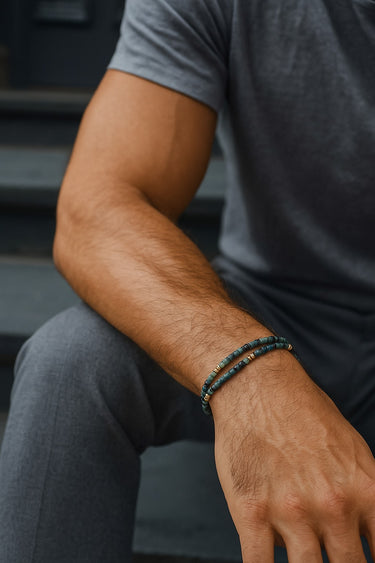 A close-up of a male model's wrist showcasing the layered geometric silhouette and dark green hues of a double-wrap tourmaline cube bracelet.
