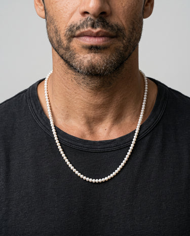 A male model wearing a dark gray  t-shirt showcasing a 4-5mm freshwarer pearl beads necklace.