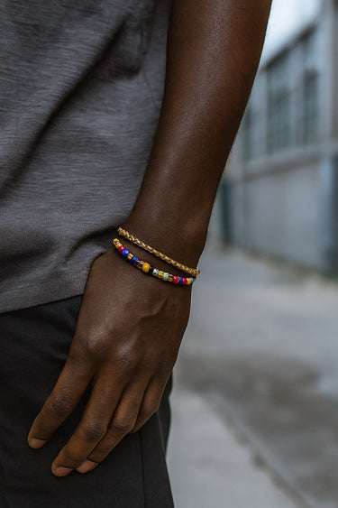 A lifestyle shot of a male model wearing a 3.5mm gold-filled chain bracelet layered with a colorful beaded bracelet, highlighting its versatile and slim profile.
