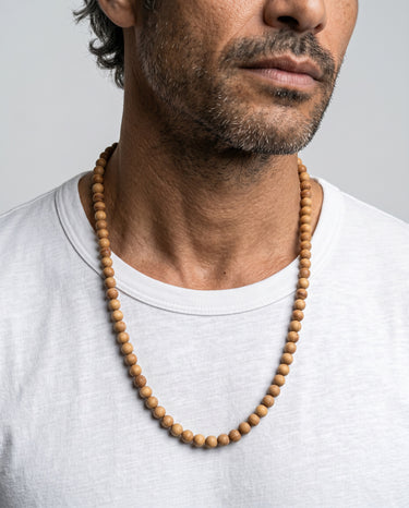 Man wearing a 6mm golden sandalwood bead necklace against a light gray background