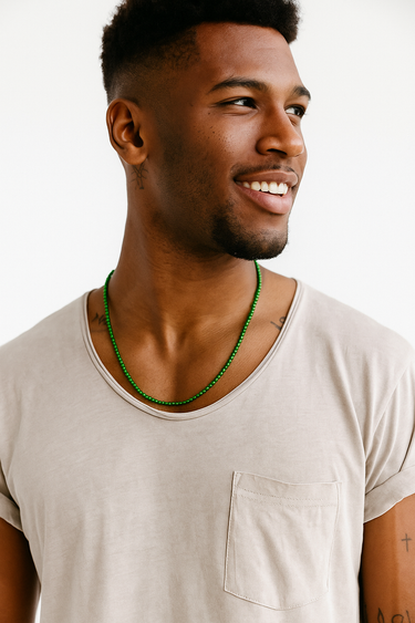 A Black male model wearing a grey t-shirt showcasing a strand of green jade beads around his neck.
