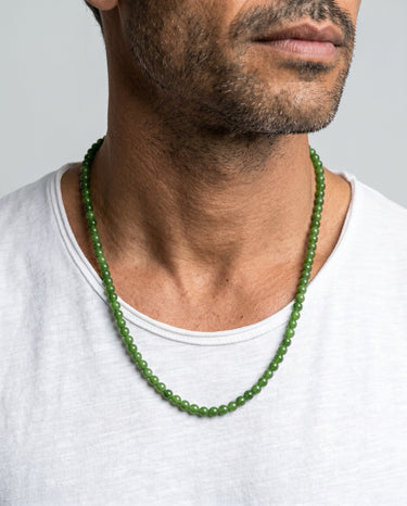 Man wearing a 6mm round green jade beaded necklace against a plain background