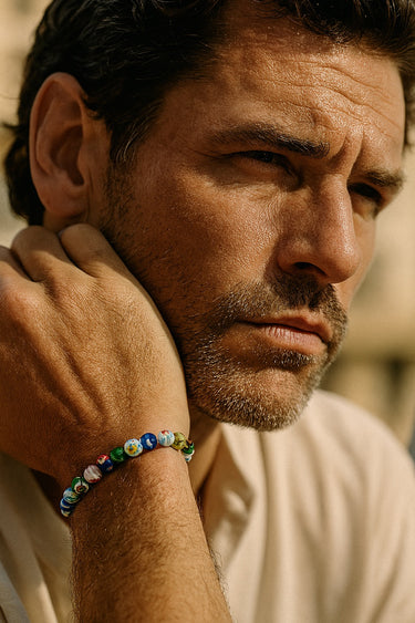 An outdoor lifestyle shot of a male model wearing the 8mm Millefiori glass bead bracelet, showcasing its vibrant natural-light shimmer.
